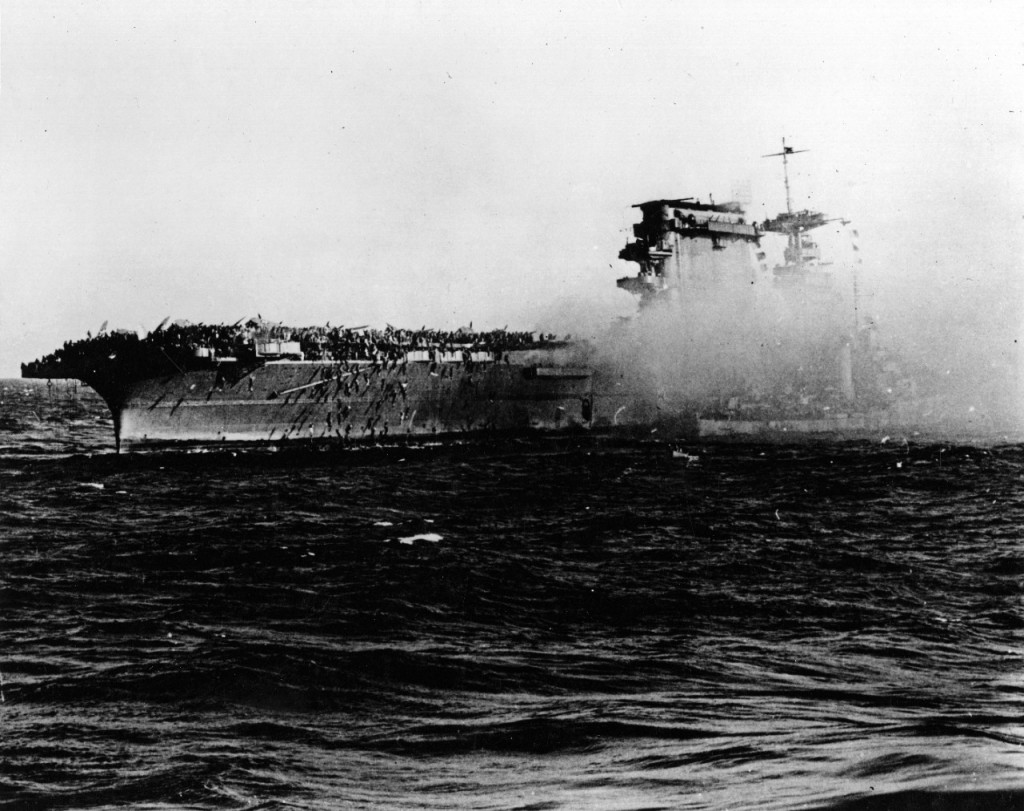 A destroyer alongside USS Lexington (CV-2) as the carrier is abandoned during the afternoon of 8 May 1942. Note crewmen sliding down lines on Lexington's starboard quarter. Credit: U.S. Navy