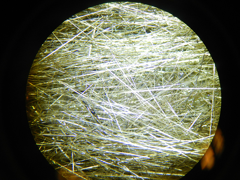 Pele's Hair - volcanic glass strands - under a microscope. Each strand is about the width of a piece of hair (hence the name) but dark droplets of cooled lava can be seen as well. Cm3826/Wikimedia Commons.