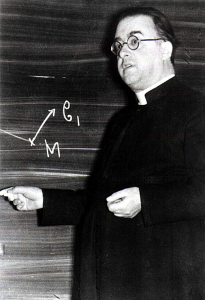a man in a priest’s cassock in front of a chalkboard